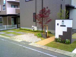 駐車スペースを大きくとり、車が止めやすいように設計。人が通るアプローチには色をつけ、きちんとした人の動線を作りました。門柱には、白い門柱の上からグレーの石材を貼り付けました。緑もふんだんに使いました。